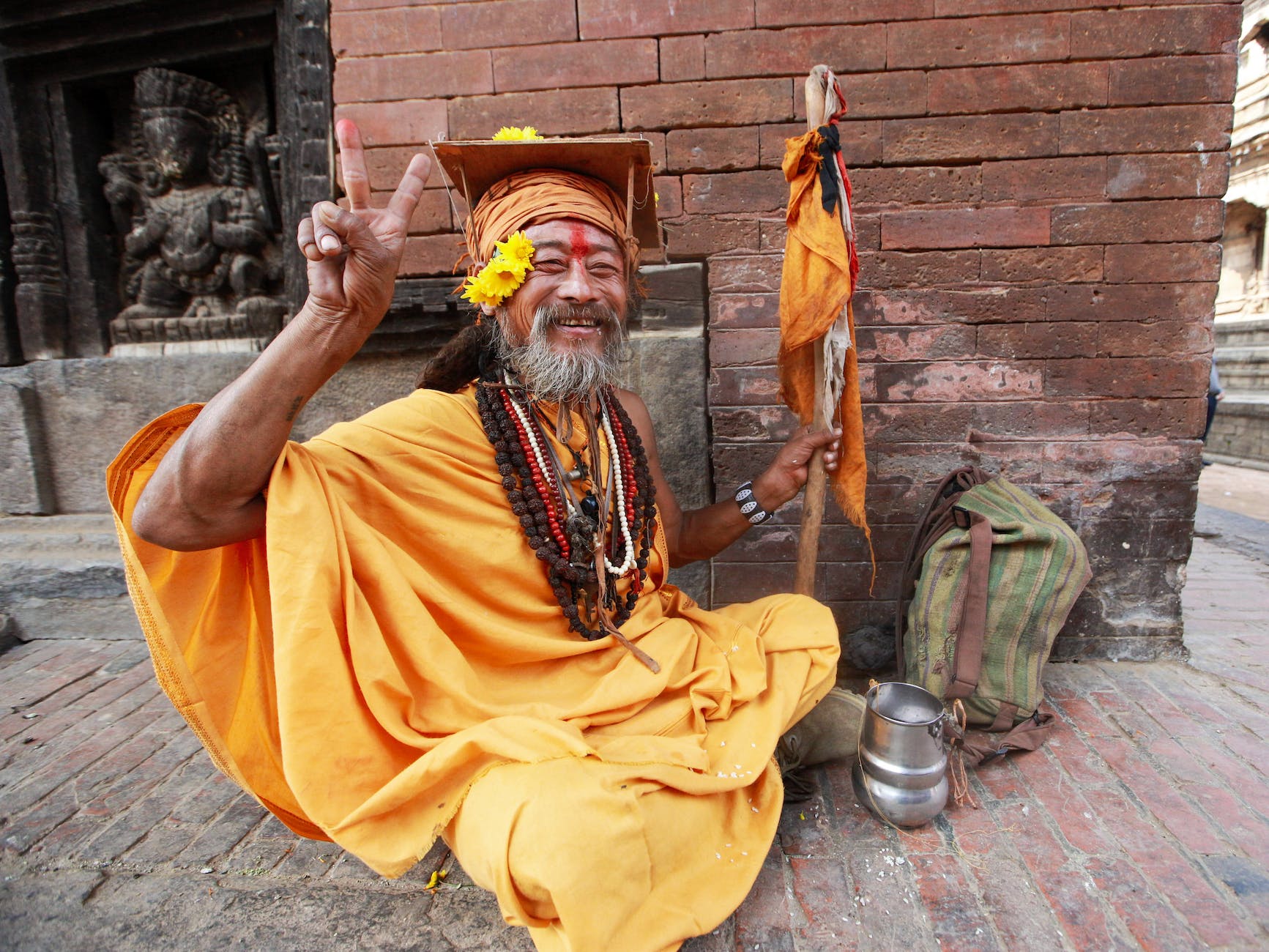 old monk smiling and sitting on the floor outside the temple